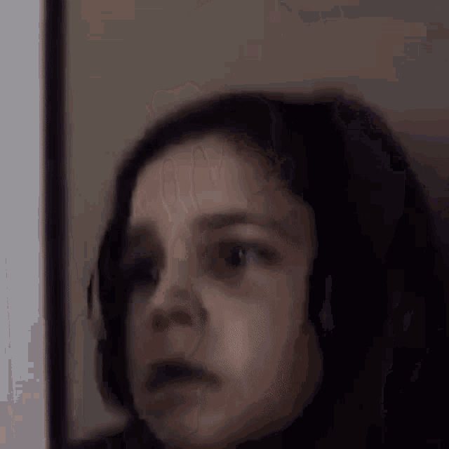 a close up of a young girl making a funny face while looking at the camera .