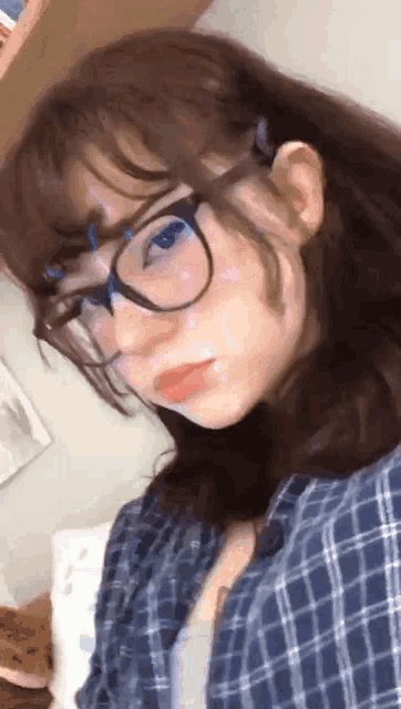 a girl wearing glasses and a plaid shirt takes a selfie