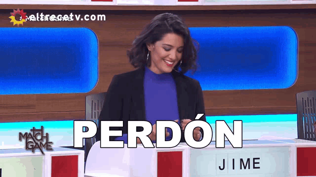 a woman sitting in front of a sign that says perdon on it