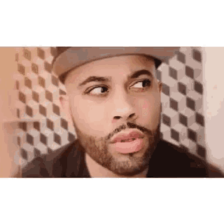 a man with a beard wearing a hat and making a funny face .