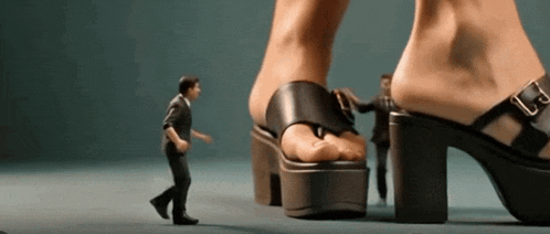 a man is walking in front of a woman 's foot wearing a pair of heels .