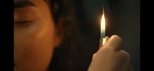 a close up of a woman lighting a lighter