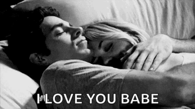 a black and white photo of a man and a woman hugging in bed .