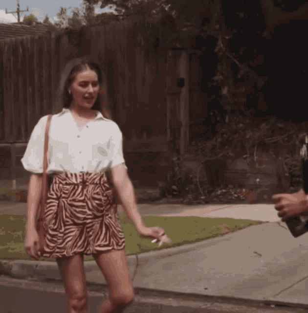 a woman in a zebra print skirt is walking down a street