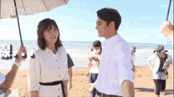 a man and a woman are standing next to each other on the beach .
