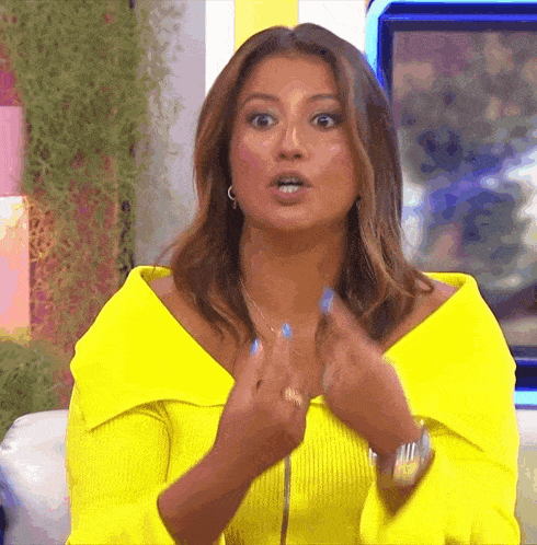 a woman wearing a yellow sweater and blue nail polish