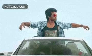 a man is driving a car with his arms outstretched and a woman is sitting in the back seat .