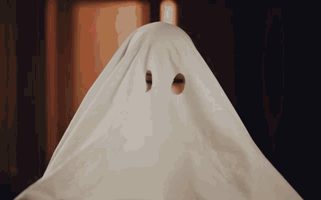 a person covered in a white sheet with two holes in the eyes