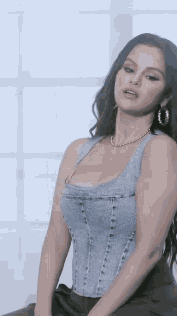 a woman is wearing a denim corset top and earrings .
