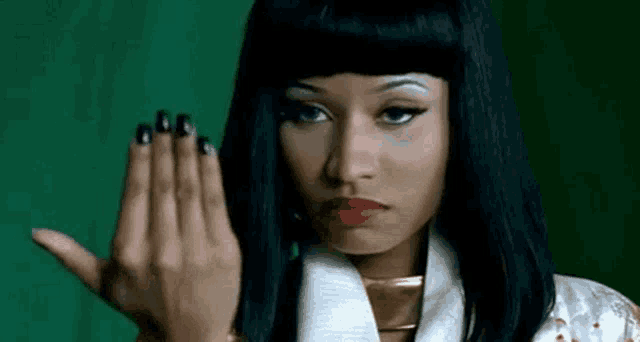 a woman with long black hair and red lips is making a hand gesture .