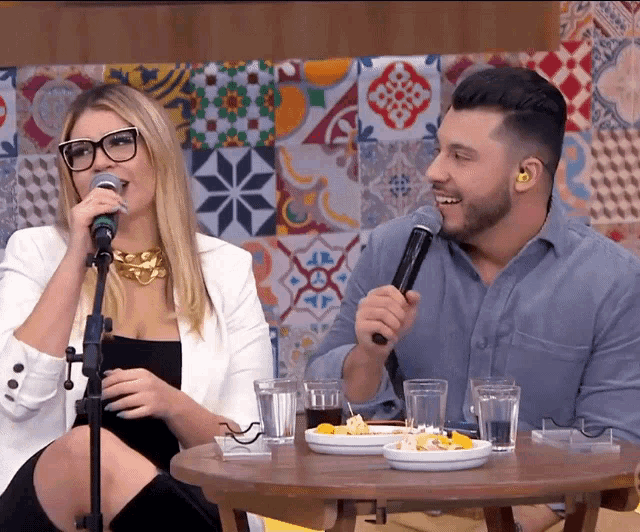 a man and a woman sitting at a table with microphones