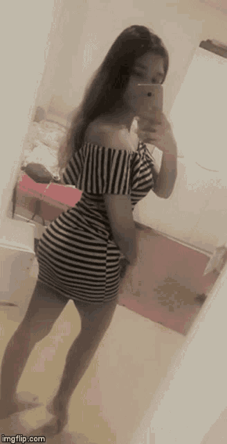 a girl in a striped dress is taking a picture of herself in the mirror