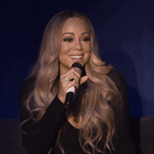 a woman is smiling while holding a microphone in her hand