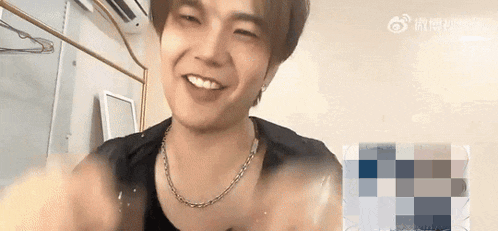a young man wearing a necklace is smiling and making a face .