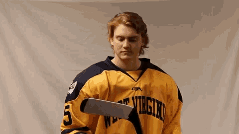 a man in a virginia jersey holds a hockey stick