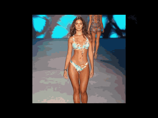 a woman in a bikini walks down the runway