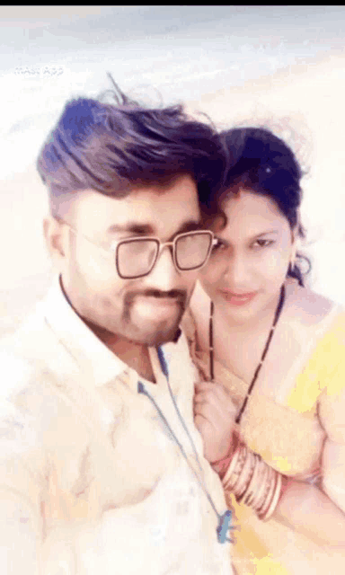 a man and a woman are posing for a picture together . the man is wearing glasses .