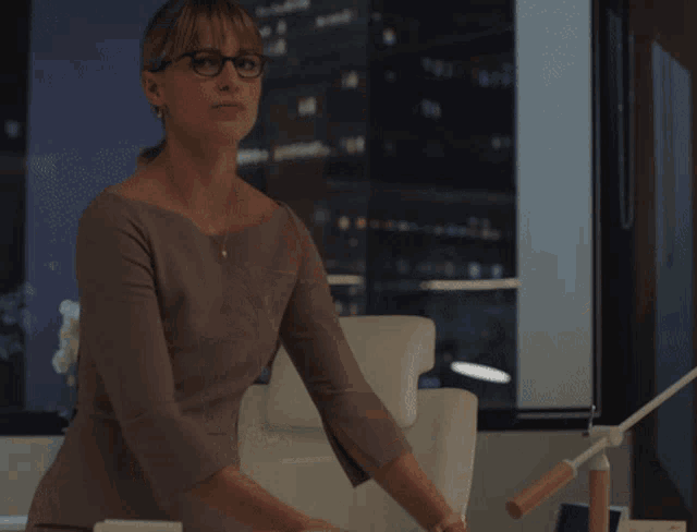 a woman wearing glasses is standing in front of a desk