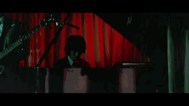 a man playing drums and a man playing saxophone in a dark room