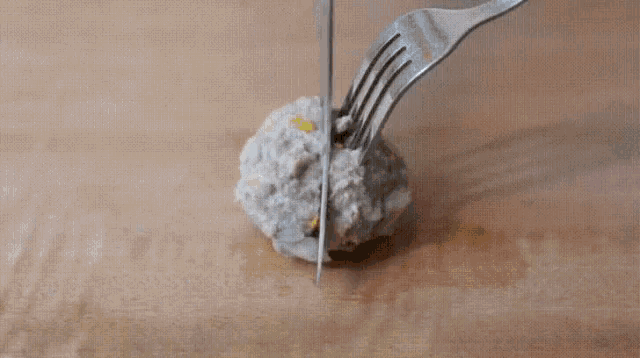 a fork is being used to cut a piece of food on a cutting board