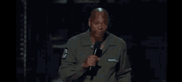a man in a green jacket is holding a microphone on a stage .