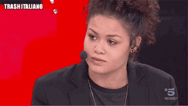 a woman with curly hair is talking into a microphone with the word totalmente above her
