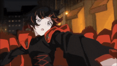 a girl in a black and red outfit stands in front of a crowd of red seats