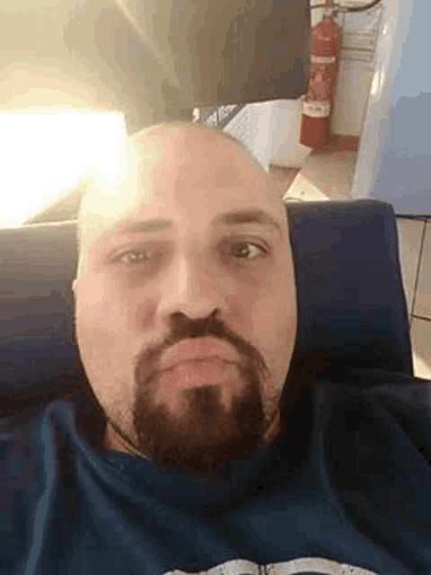 a bald man with a beard is making a funny face while sitting on a couch .