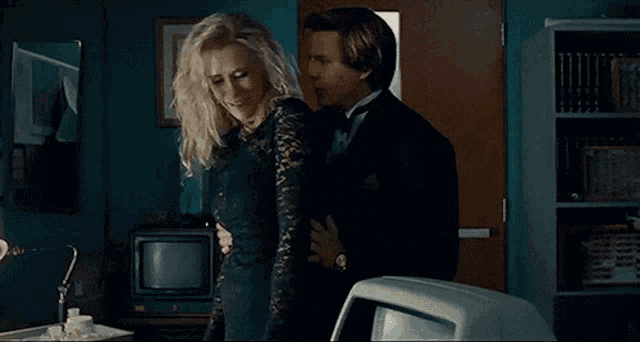 a man in a tuxedo holds a woman in a black dress