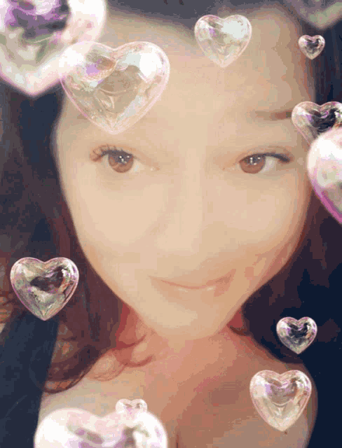 a woman surrounded by heart shaped soap bubbles on her face