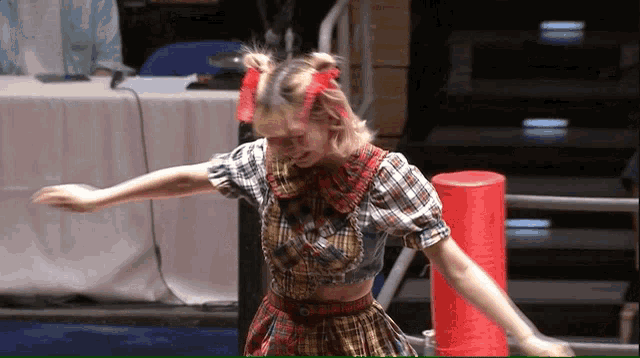 a woman in a plaid shirt is dancing in front of a table