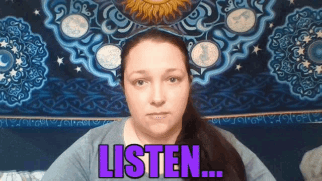 a woman is sitting in front of a tapestry that says listen on it