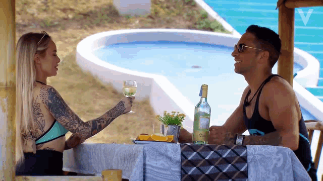 a man and a woman are sitting at a table with a bottle of tequila