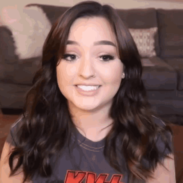 a woman is wearing a kiss shirt and smiling .