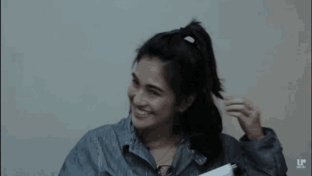 a woman is smiling while holding a piece of paper in her hand