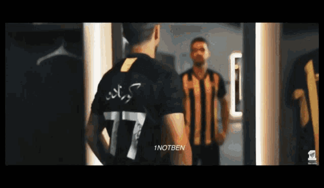 a man standing in front of a mirror wearing a jersey with the number 77