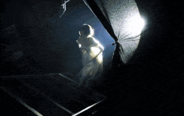 a woman in a long white dress is standing in a dark room