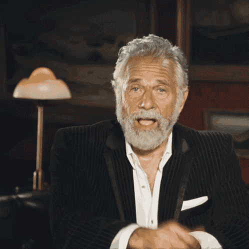 a man with a beard and a suit is pointing at the camera