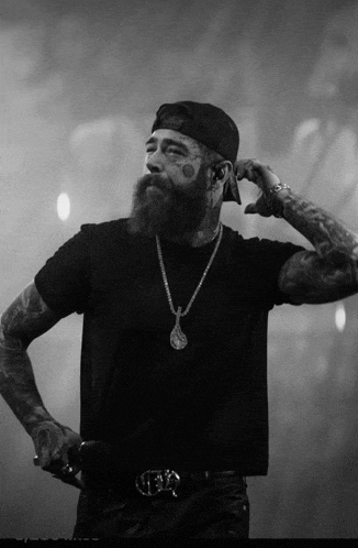 a man with a beard is wearing a black shirt and a black hat