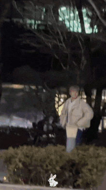 a person is standing in front of a bush with a rabbit flying in the background .