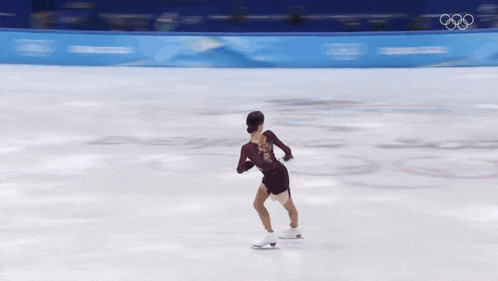 a woman is ice skating in front of a wall that says beijing 2012