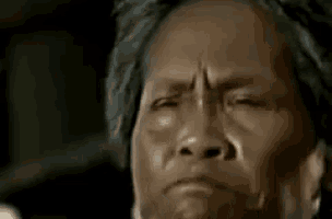 a close up of a woman yawning with her hand on her mouth .