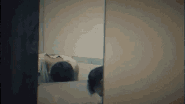 a person is looking at their reflection in a mirror .