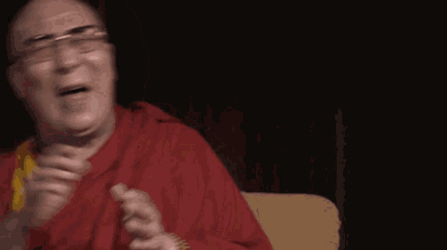 a man wearing glasses and a red robe laughs