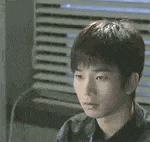 a young man is sitting in front of a window and looking at something .