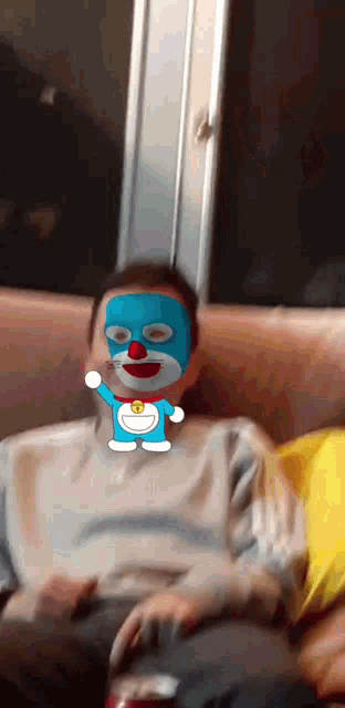 a person with a doraemon mask on their face sitting on a couch