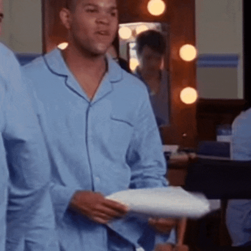 a man in a blue pajama shirt is holding a pillow in front of a mirror