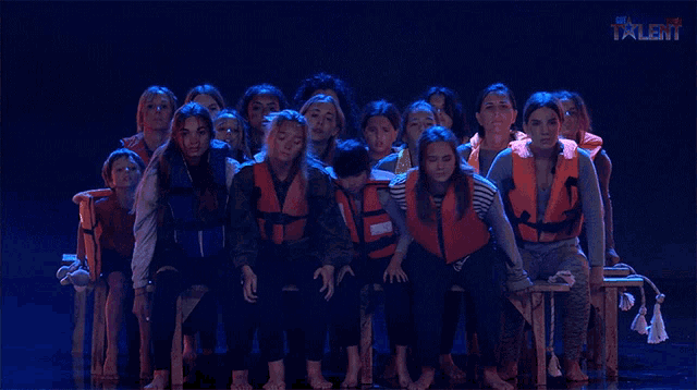 a group of people wearing life jackets are sitting on a stage in front of a sign that says " new talent "
