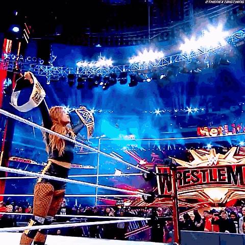 a woman is standing in a wrestling ring holding a world heavyweight championship .