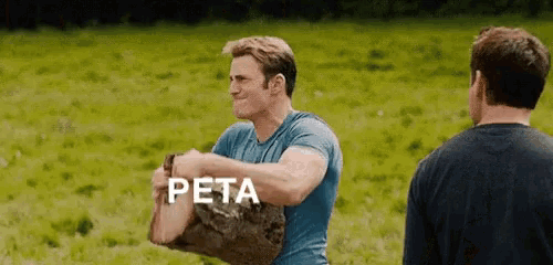 a man in a blue shirt is carrying a log with the word peta written on it